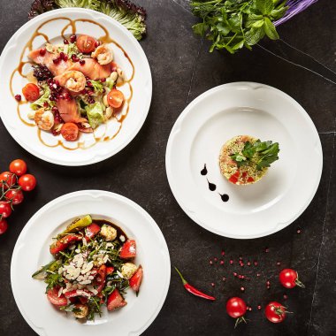 Çeşitli et ve sebze salata somon, karides, domates, baharat, otlar ile ayarla, Yeşiller görünümü Top. Deniz ürünleri korkumu, kuskus salatası ve Mozarella Peyniri beyaz plakaları ile yeşil salata