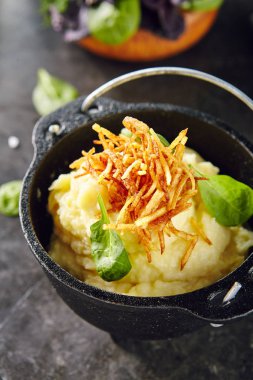 Püresi patates ile dekore edilmiş soğan kavrulmuş ve dökme demir yeşillik yakın Pot. Krem şanti patates püresi seçici üzerine tereyağı ile odak arka plan bulanık