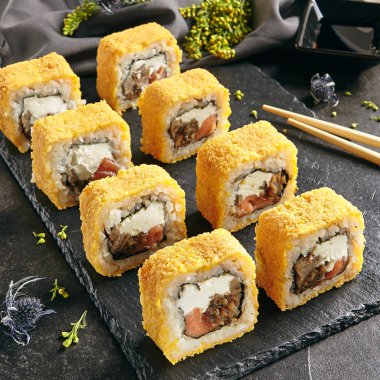 Sıcak çıtır derin kızarmış suşi rulo somon ve Philadelphia krem peynir içinde. Tempura Maki kümesiyle ton balığı ve doğal siyah taş arduvaz arka plan üstten görünüm üzerinde Nori deniz yosunu