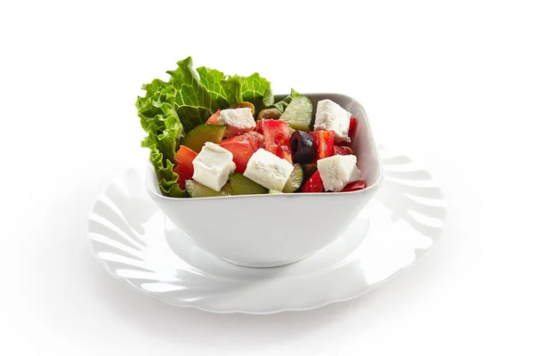 Greek Salad in Light Plate Isolated on White Background. Villages Salad or Horiatiki Made with Pieces of Tomatoes, Diced Cucumbers, Onion, Feta Cheese and Olives