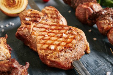 Orta nadir domuz Loin barbekü biftek bir şiş baharatlar ile kapatın. Domuz eti ile seçici odak üstünde siyah arka plan bulanık saptırılmış ızgara pirzola makro fotoğraf