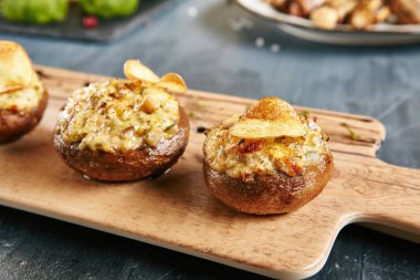 Suluguni peynir ile doldurulmuş petrol pişmiş, sarımsak ve otlar kapatalım. Vejetaryen yemek ızgara mantar kapakları, doğranmış sebze, baharatlar ve patates kızartması