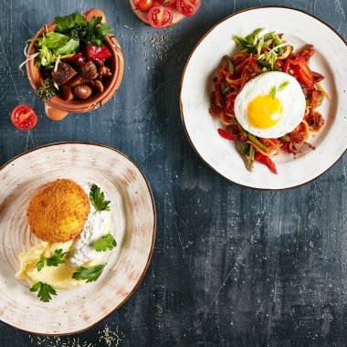 Kızarmış Tavuk Kiev ile Restoran ana tabii ayarla, ev yapımı Kaurma Lagman, kavrulmuş Türkiye'de lüks siyah seramik Pot üstten görünüm taş. Çeşitli et yemekleri sebze düz Lay koleksiyonuyla