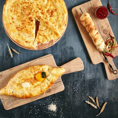 Gürcistan ve Acara Khachapuri yemekleri rustik arka plan siyah üstten görünüm üzerinde kümesi. Ev yapımı acaralı Khachapuri, Megrelian ve peynirli ızgara Khachapuries koleksiyonu yakın