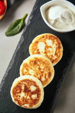 Üstten görünüm lezzetli aromatik lor, ekşi krema ile krep. Altın kabuk ile şekerli tatlı kara tahta satırındaki Servis. İştah açıcı kahvaltı konsepti