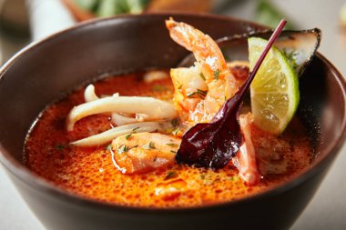 Baharatlı Tay tom yam deniz mahsulleri çorbası ile yakın çekim portre. Gerçek gurme için çanak yaprakları ve kireç dilim dekore edilmiş. Japon gıda kavramı. Arka plan bulanık