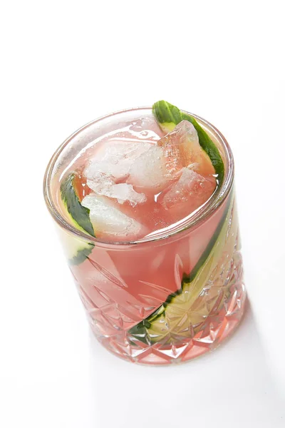 Garden Pears Alcohol Cocktail with Pear, Berries and Cucumber in a Crystal Glass Isolated on White Background. Light Pink Iced Gin Tonic with Sliced Cucumbers and Ripe Fruits Close Up