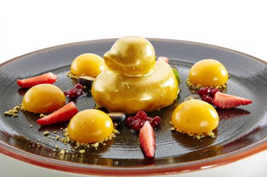 Meyve tatlı çilek ve beyaz arka plan üzerinde izole Mango küre ile. Enfes çanağı altın Ducky pasta kayısı ile hizmet veren, üzüm ve çilek zarif restoran siyah plaka üzerinde Kapat