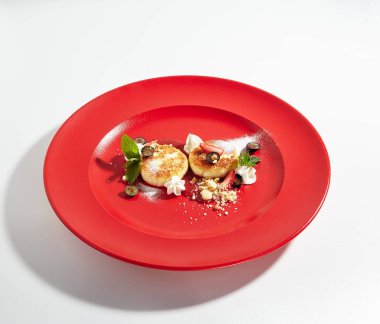 Makro fotoğraf Berry sos ve beyaz arka plan üzerinde izole zarif restoran kırmızı plaka üzerinde ev yapımı krem peynir krep. Kuark krep, Tvorozhniki veya Syrnyky yakından