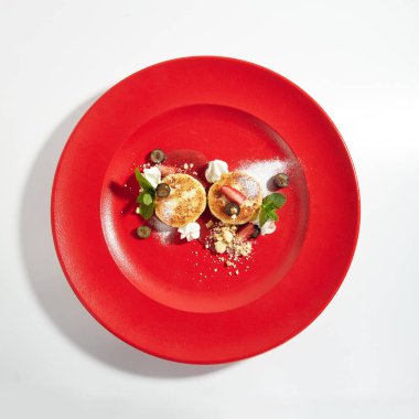 Makro fotoğraf Berry sos ve beyaz arka plan üzerinde izole zarif restoran kırmızı plaka üzerinde ev yapımı krem peynir krep. Kuark krep, Tvorozhniki veya Syrnyky yakından