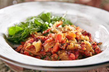 Vejeteryan pişmiş sebze salatası rustik tarzı zemin üzerine kapatın. Makro fotoğraf kızarmış, kabak, domates, tatlı biber, taze dereotu ve maydanoz eski seramik kase komposto