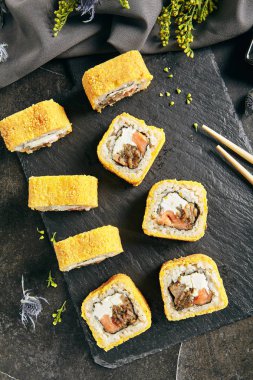 Sıcak çıtır derin kızarmış suşi rulo somon ve Philadelphia krem peynir içinde. Tempura Maki kümesiyle ton balığı ve doğal siyah taş arduvaz arka plan üstten görünüm üzerinde Nori deniz yosunu