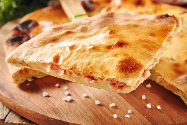 Taze pişmiş parça somon ile doldurulmuş pasta patates ve peynir ile seçici odak kapat. Lezzetli kırmızı balık Tart hizmet yeşillik ve rustik ahşap zemin üzerine baharat ile dilim