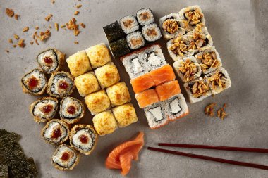 Büyük çeşitli Maki Sushi gri arka plan üzerinde en iyi görünümü ayarlayın. Norimaki pişmiş, kahverengi ve beyaz soslar düz Lay Kappamaki liberalizmin koleksiyonu somon, ton balığı rendelenmiş peynir ile tepesinde ile dekore edilmiş olan