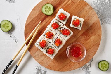 Uramiaki Sushi doğal ahşap arka plan üst görünümü Kırmızı somon havyar ile tepesinde. Modern gri grunge zemin üzerinde çiğ balık, salatalık, avokado ve Philadelphia krem peynir ile Nori maki Rolls