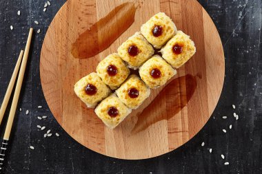 Uram suşi peynir ve sos Ham pirinç tahıllar ve Chopsticks çevrili ile tepesinde. Pişmiş Nori maki doğal ahşap ve siyah taş arka plan üst görünüm