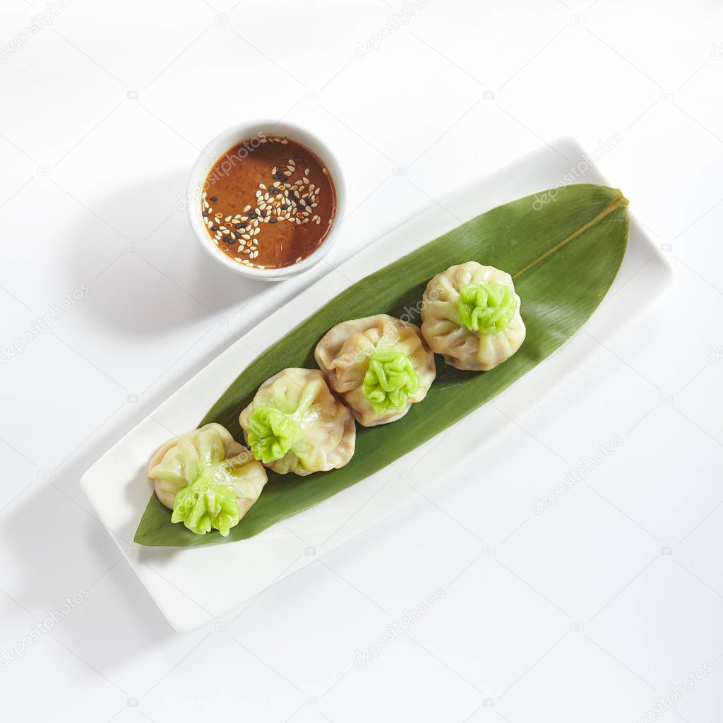 Luxury Serving Vegetarian Dim Sum, Dimsum or Momos on a Banana Leaf with Spicy Sauce Isolated on White Background. Chinese Restaurant Wontons or Dumplings Top View