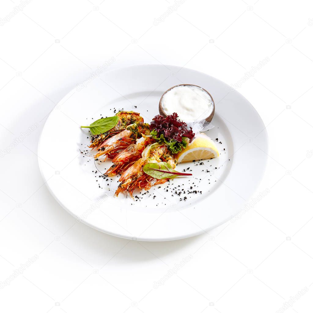 Hot Appetizer of Grilled Tiger Prawns with Green Oil on Elegant Restaurant Plate Isolated on White Background. Warm Starter with Fried King Shrimps with Herbs, Spices, Sauce, Lemon, Greens Close Up