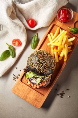 Pişmiş biber sulu sığır pirzola peynir sosu ve Chutney ile siyah Burger portresi. Arka planda patates kızartması. Açık ahşap rustik tahta