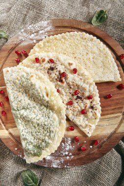 Rustik masa örtüsü çuval bezi zemin üzerine Kutabs grup. Qutab, Kutab veya fırında tavuklu ince haddelenmiş kısaca pişmiş bir dışbükey zor durumda üst görünümde olan hamuru ile peynir ve yeşillik olduğunu