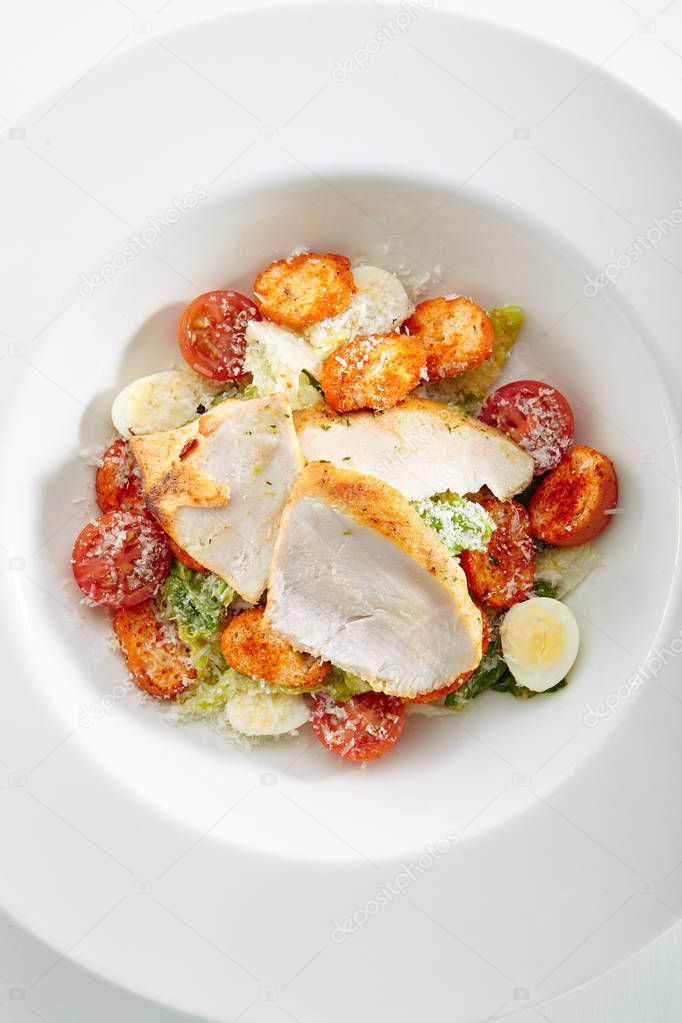 Caesar Salad with a Crispy Chicken Top View. Restaurant Main Course with Turkey Fillet, Quail Eggs, Mini Baguette Rusks, Cherry Tomatoes, Lettuce Leaves, Sauce and Parmesan Cheese