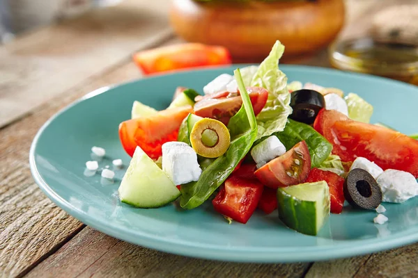 Griechischer Salat in blauem Teller auf rustikalem Holzhintergrund — Stockfoto