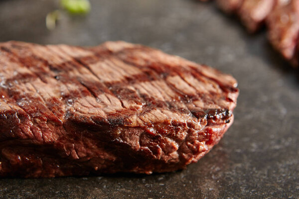 Hot Grilled Whole Denver Steak on Black Stone Background. Fresh Juicy Medium Rare Beef Grillsteak. Barbecue Meat Close Up