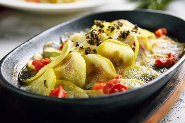 Fisk bakad under skivad potatis i metall matlagning potten närbild — Stockfoto