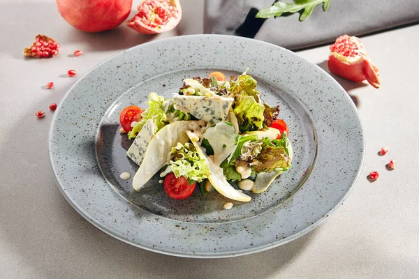 Salad with sliced pears, gorgonzola cheese, greens and pine nuts