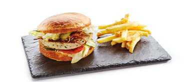 Soğan, domates sosu, salatalık turşusu, yeşil marul, Türkiye, peynir ve patates kızartması garnitür ile taze tavuk Burger. Hamburger ya da Chickenburger doğal siyah taş plaka üzerinde izole beyaz