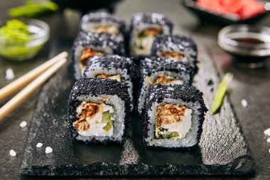 Pirinç, krem peynir, hayel, salatalık, uçan balık siyah havyar ve nori closeup ile unagi maki rulo Makro atış. Taze japon uramaki siyah kayrak plaka arka plan üzerinde tobiko ile rulo