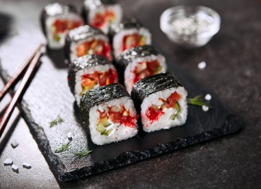 Krem peynir, somon, geyik balığı, pirinç, salatalık, uçan balık havyar ve nori ile ejderha rulo Makro fotoğraf. Doğal koyu taş arka plan üzerinde çiğ kırmızı balık ve tobiko ile Dragon unagi maki rulo yakın