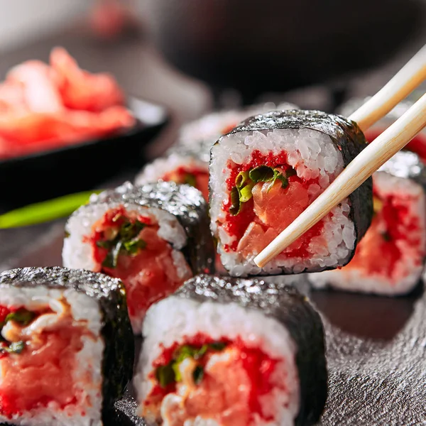 Chopstick Segurando Rolos Sushi Salmão Com Cebolas Verdes Caviar Vermelho — Fotografia de Stock