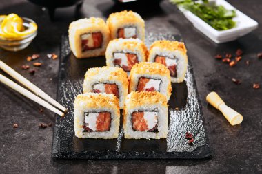 Krem peynir, çiğ somon, domates ve nori yosun ile sıcak gevrek tempura maki suşi rulo Makro atış. Doğal siyah taş kayrak arka plan closeup üzerinde derin kızarmış uramaki rulo seti