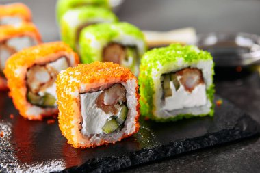 Pirinç, krem peynir, kızarmış karides, salatalık, uçan balık havyar ve nori ile Makro shot uramaki suşi rulo. Çubukları closeup ile Japon restoranında Taze renkli rulo