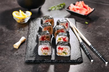 Chopsticks closeup ile Japon restoranında suşi rulo Makro atış. Pirinç, kızarmış somon, uçan balık havyar, salatalık ve baharatlı sos ile Suşi rulo