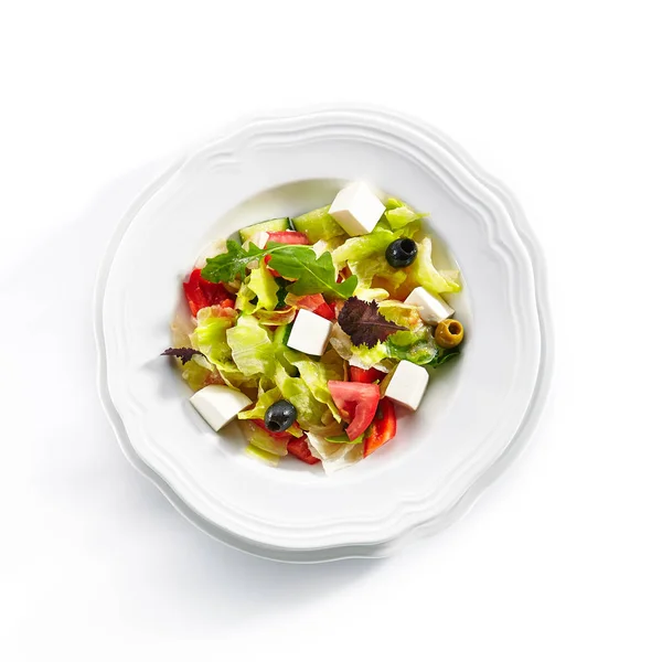 Vue du dessus de la salade grecque dans une assiette légère isolée sur fond blanc — Photo