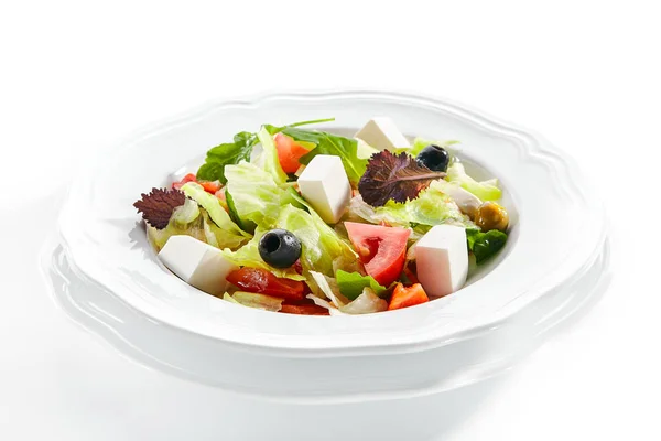 Макрошот греческого салата в светлой пластине, изолированный на белом фоне — стоковое фото