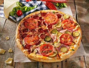 Pizza salam ile ikiye başka bir şeydir - ham salatalık turşusu ve sebze ile ahşap kurullarında dilimlenmiş domates ile