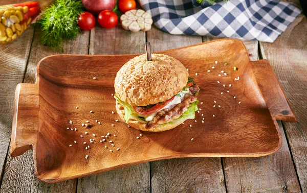 Burger Grill Restaurant Menu - Delicious Bacon Burger on Wood Plate. Rustic Wooden Table and Ingredients on Background