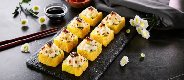 Fırında peynir kapağı ve unagi soslu tempura sıcak rulo. Suşi restoran menü öğesi. Geleneksel japon mezesi, asya mutfağı. Ahşap tabakta lezzetli doğu mezesi yakın