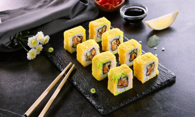 Tempura rulo geleneksel Japon çanak. Çiğ somon, el balığı ve salatalık ile suşi. Siyah tabakta Asya yemekleri ve yemek çubukları. Japonya restoran yemek konsepti. Modern gurme yemekler, lezzetli akşam yemeği