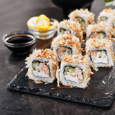 Krem peynir, kızarmış somon, ton balığı taları veya kurutulmuş bonito, salatalık, nori ile uramaki suşi rulo Makro atış. Japon restoran closeup taze katsuobushi rulo