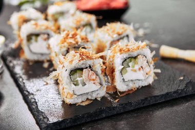 Krem peynir, kızarmış somon, ton balığı taları veya kurutulmuş bonito, salatalık, nori ile uramaki suşi rulo Makro atış. Japon restoran closeup taze katsuobushi rulo