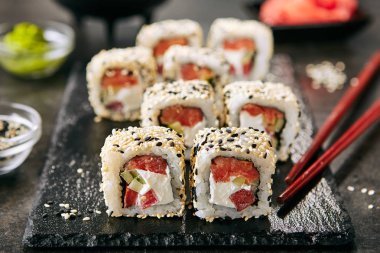 Pirinç, krem peynir, domates, salatalık, susam ve nori yakın Tokyo somon uramaki suşi. Füme balık ve taze sebze ile Japon gıda uramaki rulo Makro atış