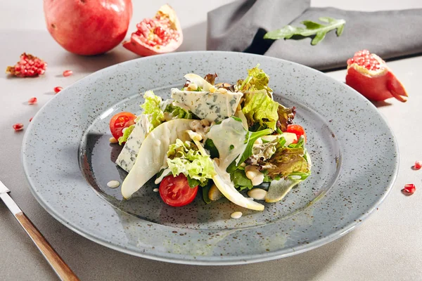 Salad with sliced pears, gorgonzola cheese, greens and pine nuts
