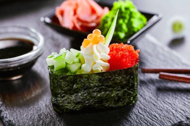 Salatalık ve masago havyar ile lezzetli gunkan. Japon mutfağı restoran menü öğesi. Geleneksel doğu yemeği, ulusal yemek. Lezzetli suşi, ahşap tabak tasnif üzerinde oryantal gıda closeup