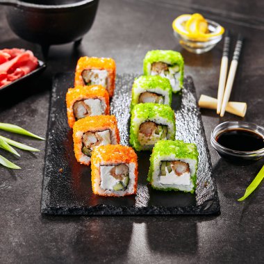 Pirinç, krem peynir, kızarmış karides, salatalık, uçan balık havyar ve nori ile Makro shot uramaki suşi rulo. Çubukları closeup ile Japon restoranında Taze renkli rulo