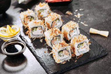 Krem peynir, kızarmış somon, ton balığı taları veya kurutulmuş bonito, salatalık, nori ile uramaki suşi rulo Makro atış. Japon restoran closeup taze katsuobushi rulo