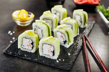Krem peynir, kar yengeç, salatalık, uçan balık havyar, mayonez, limon ve nori closeup ile Uramaki suşi rulo. Koyu bulanık arka plan üzerinde deniz ürünleri suşi Makro çekim